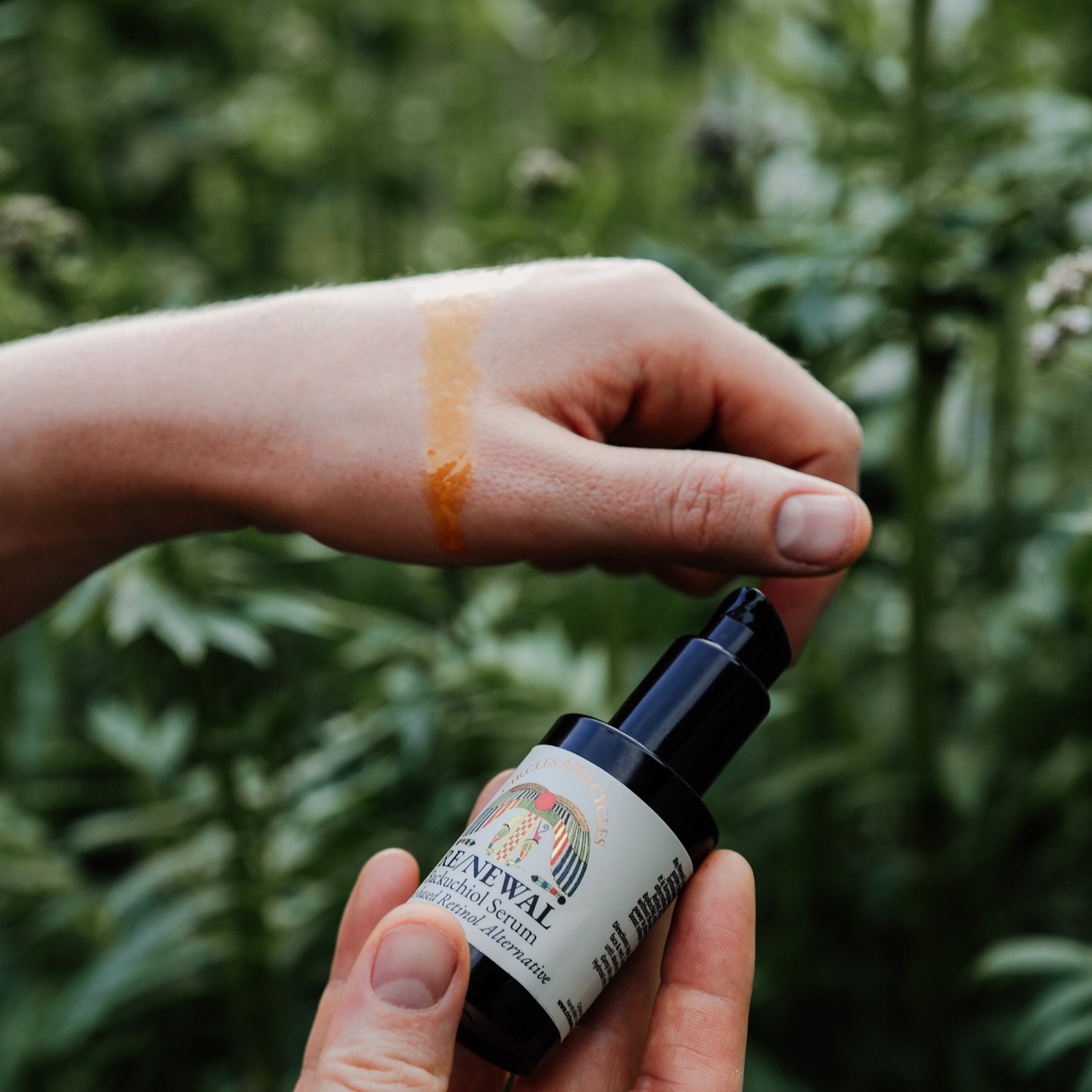 Hand holding a small bottle labeled 'Renewal' against a green leafy background