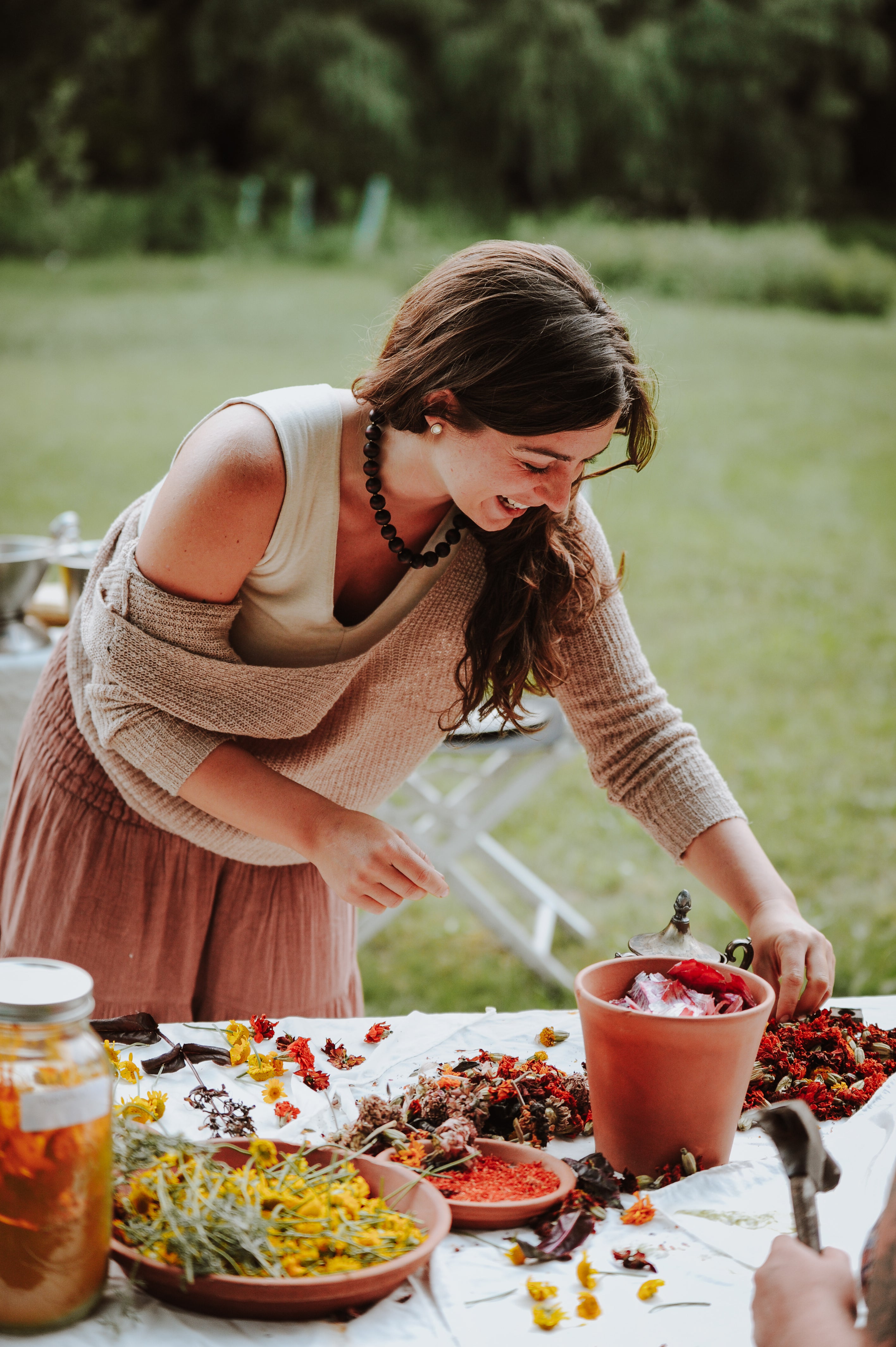 Woman arranging flowers at a table outdoors